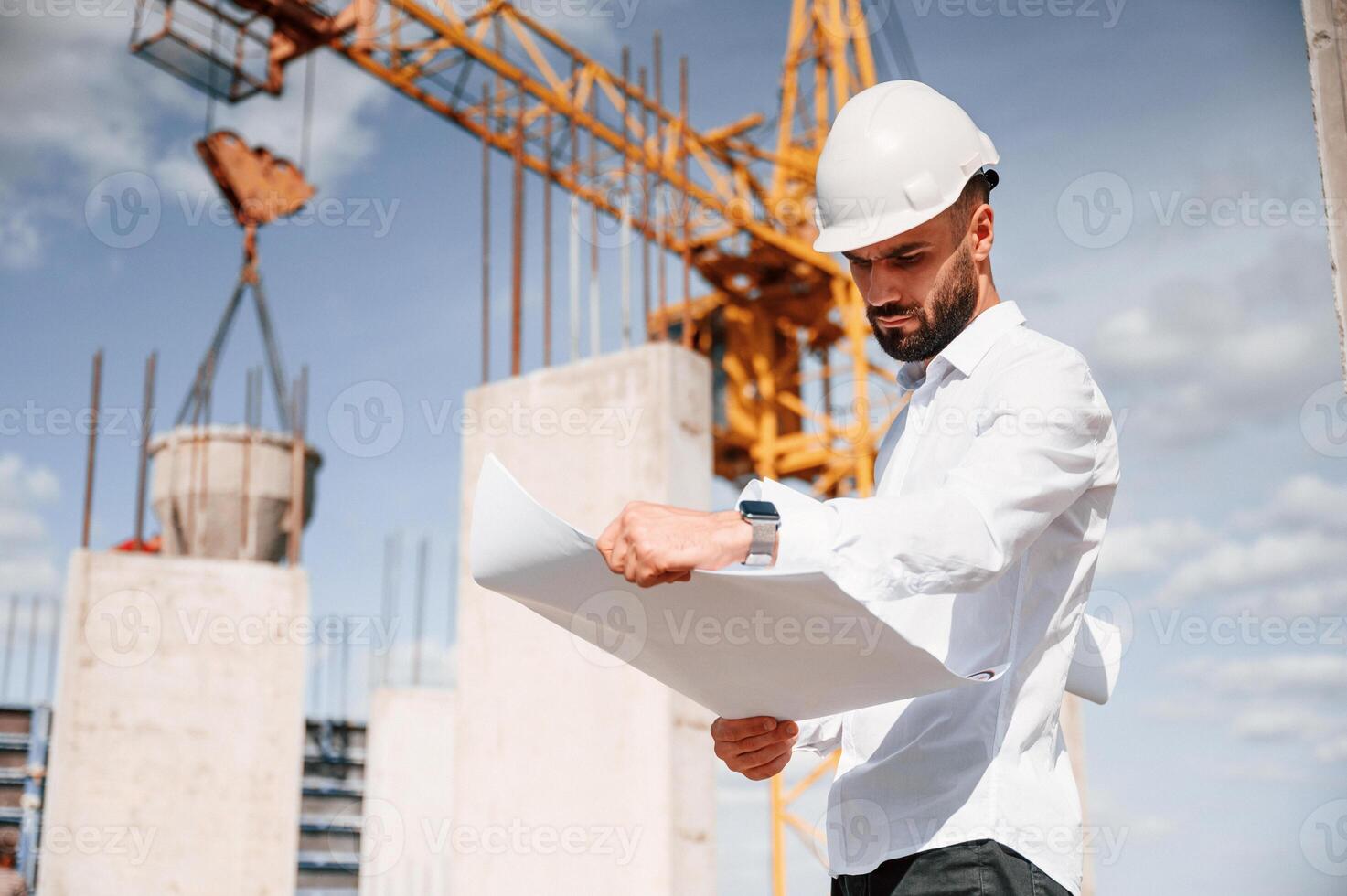 With ,plan in hands. Man in uniform is working on the ,construction site photo