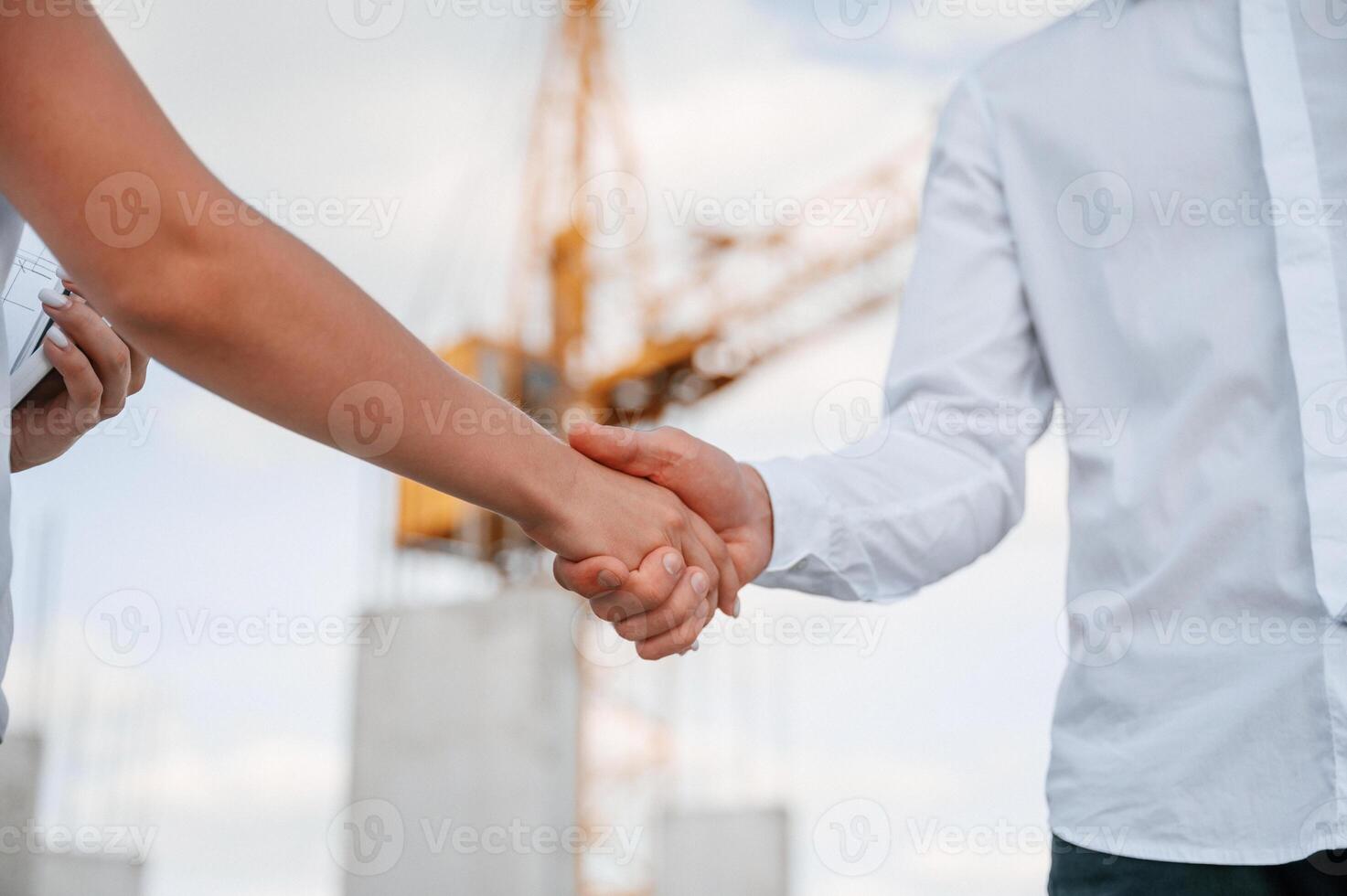 Close up view. Doing handshake. Man in uniform working with woman on the construction site photo