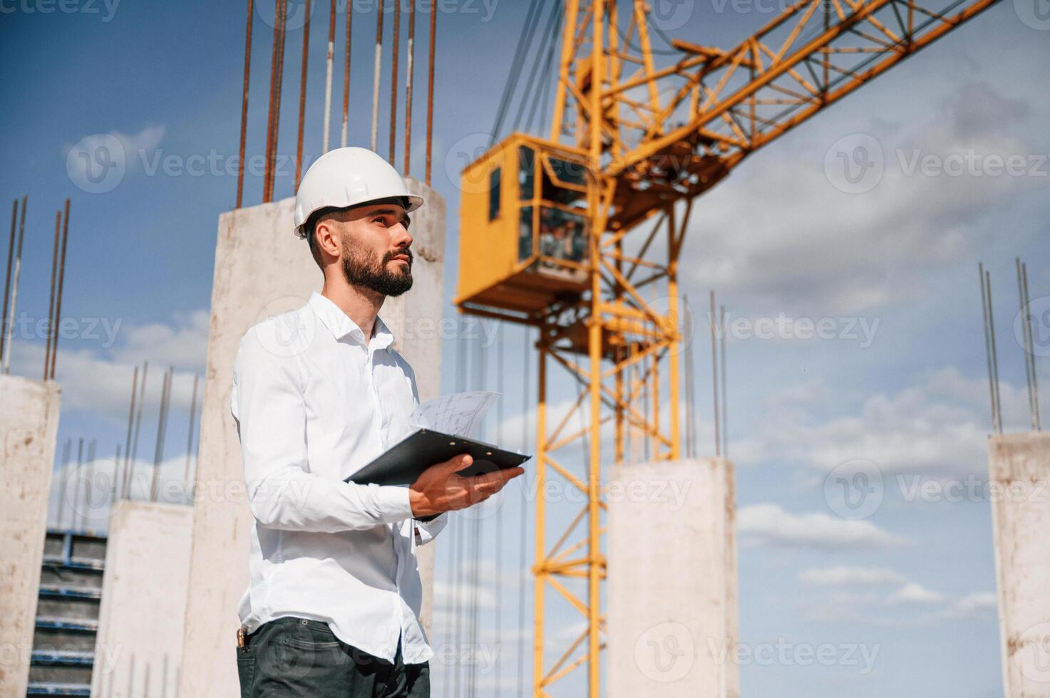 Inspector with notepad is ,standing on the construction site photo