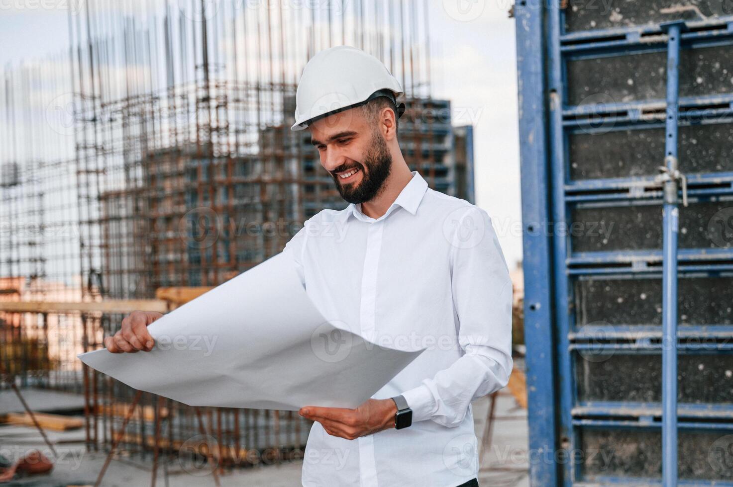 Reading the plan. Man, in uniform ,is working on the construction site photo