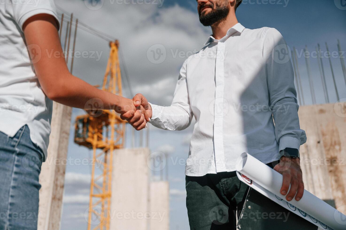 Doing handshake. Successfu,l agreement. Man in uniform working with woman on the construction site photo