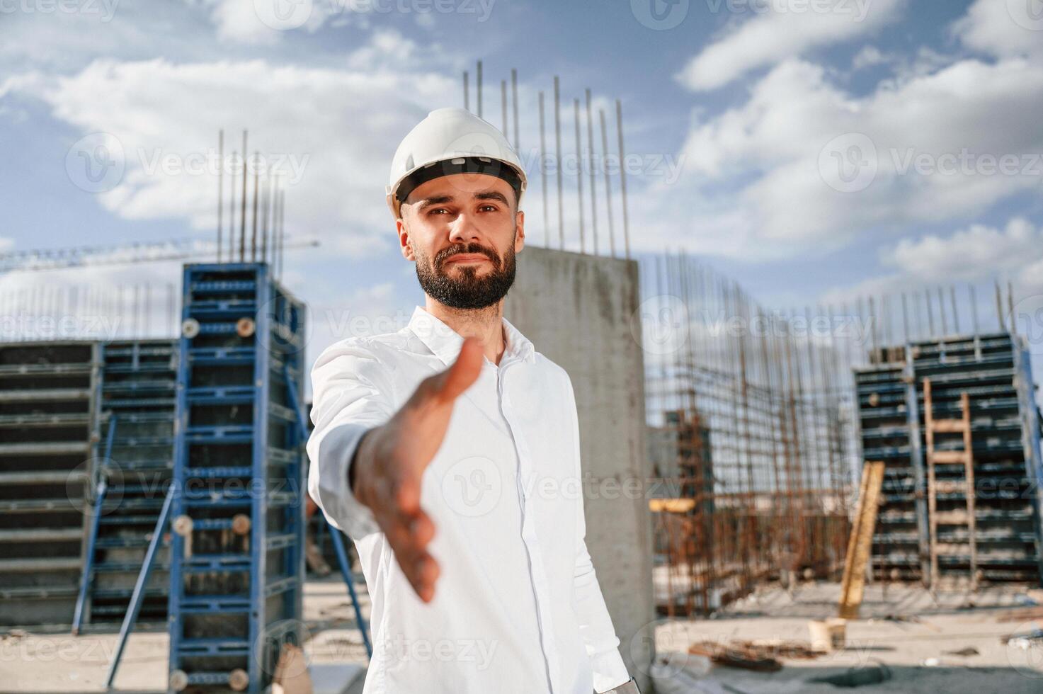 Engineer ,extends his hand. Man in uniform ,is working on the construction site photo