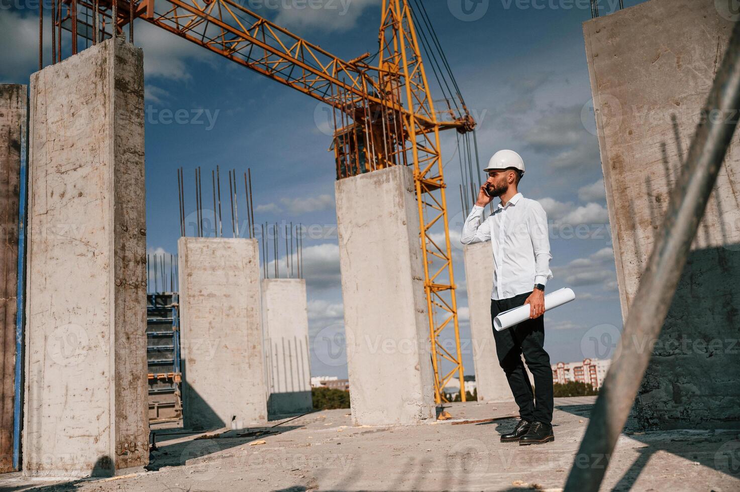 Talking ,by phone and holding ,document in hands. Man in uniform is working on the construction site photo