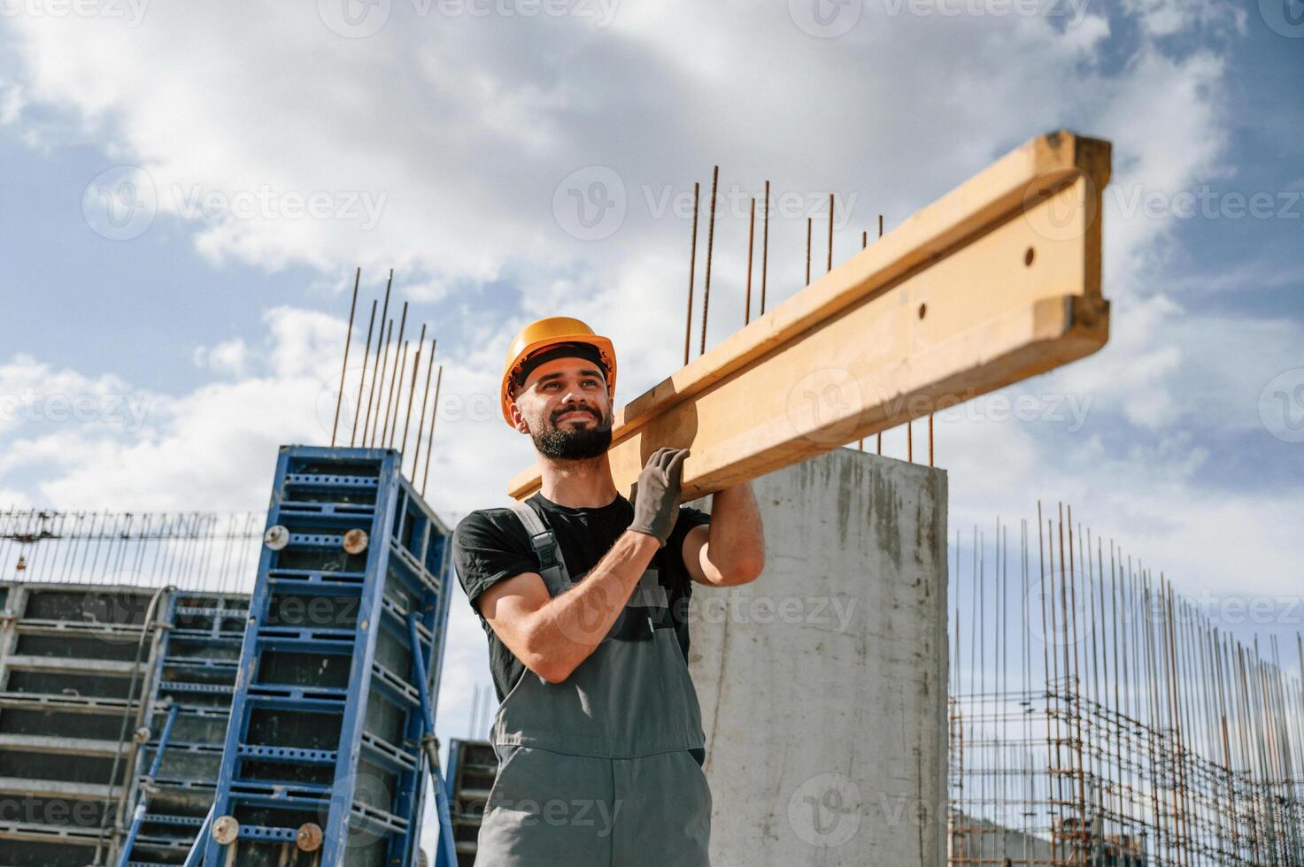 Carrying wooden plank. Man in uniform is working on the construction ,site photo