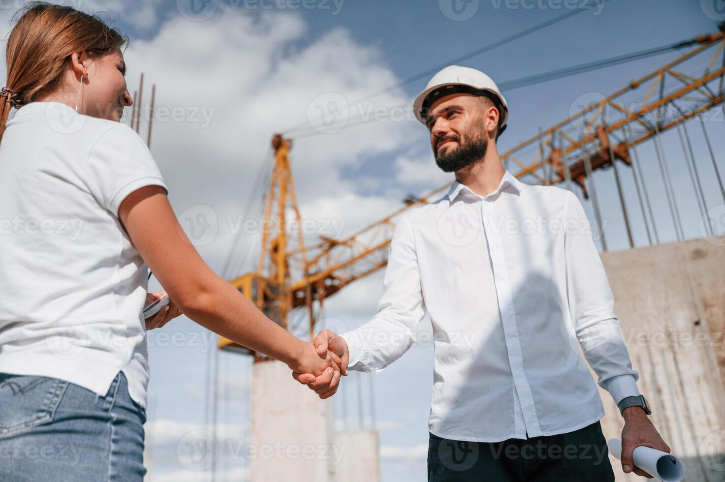 Doing ,handshake. Successful agreement.. Man in uniform working with woman on the construction site photo