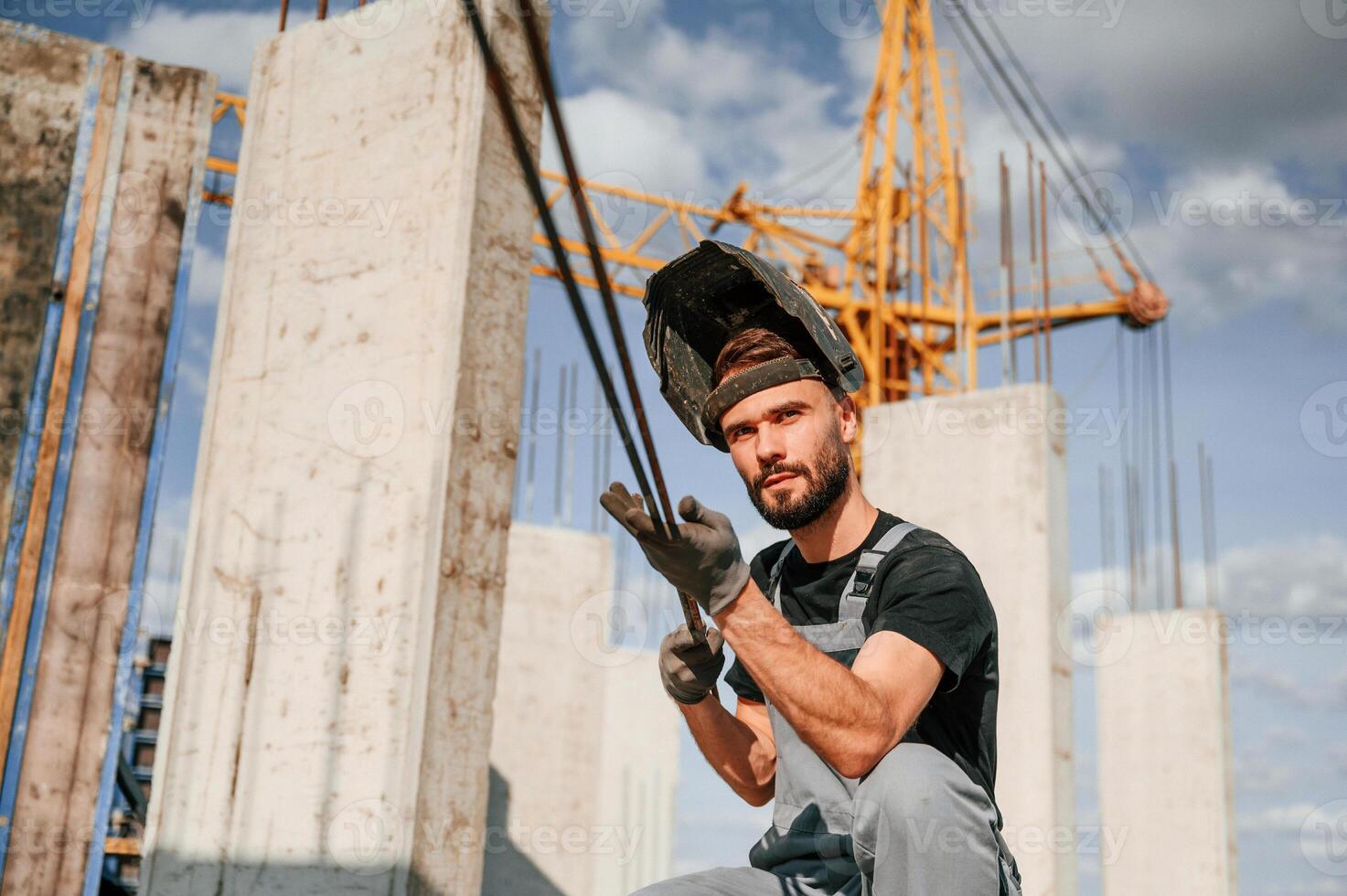 In welding mask. Man in uniform is, working on the construction site photo