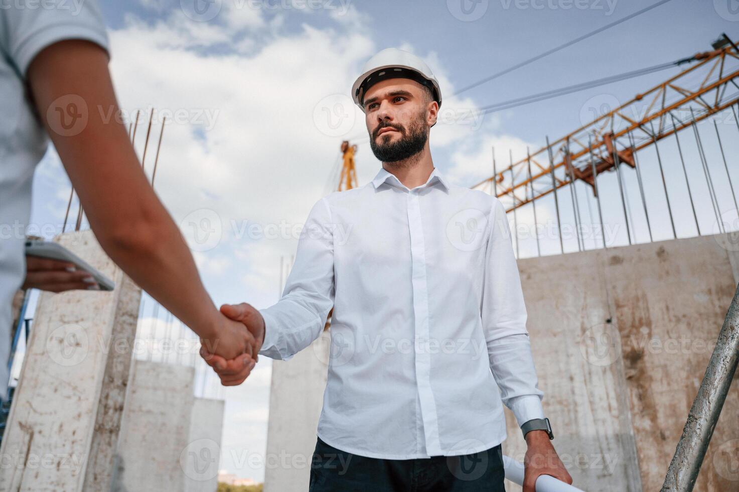 Doing handshake. Successful agreement. Man in uniform working with woman on the construction site photo