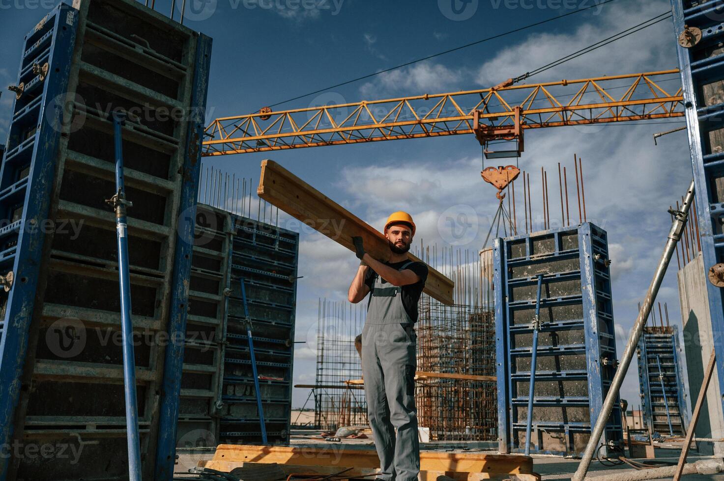 Yellow colored ,wooden plank. Man in uniform is working on the construction site photo