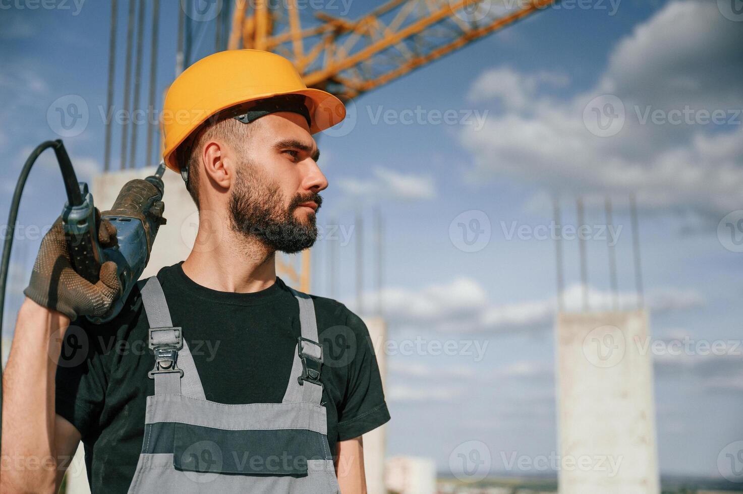 Portrait of man that is, in uniform with the drill on the construction site photo