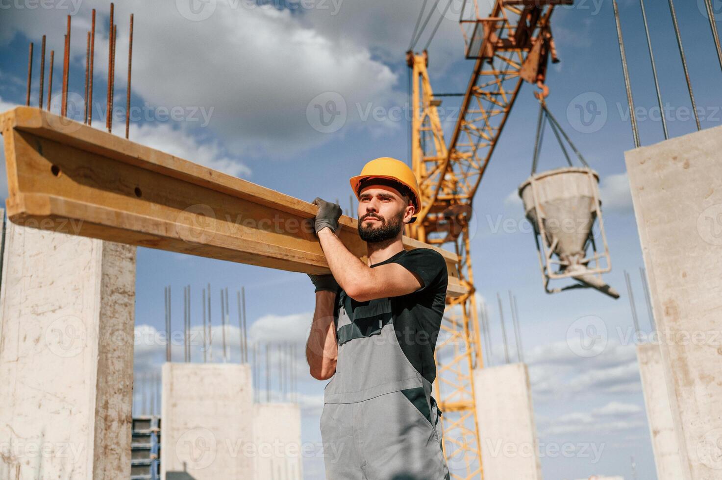 Front view of ,man that is in uniform ,holding wooden plank on the construction site photo