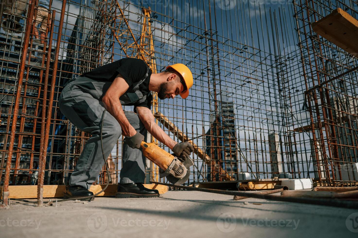 Using grinding machine to cut metal pieces. Man in uniform is working on the construction site photo