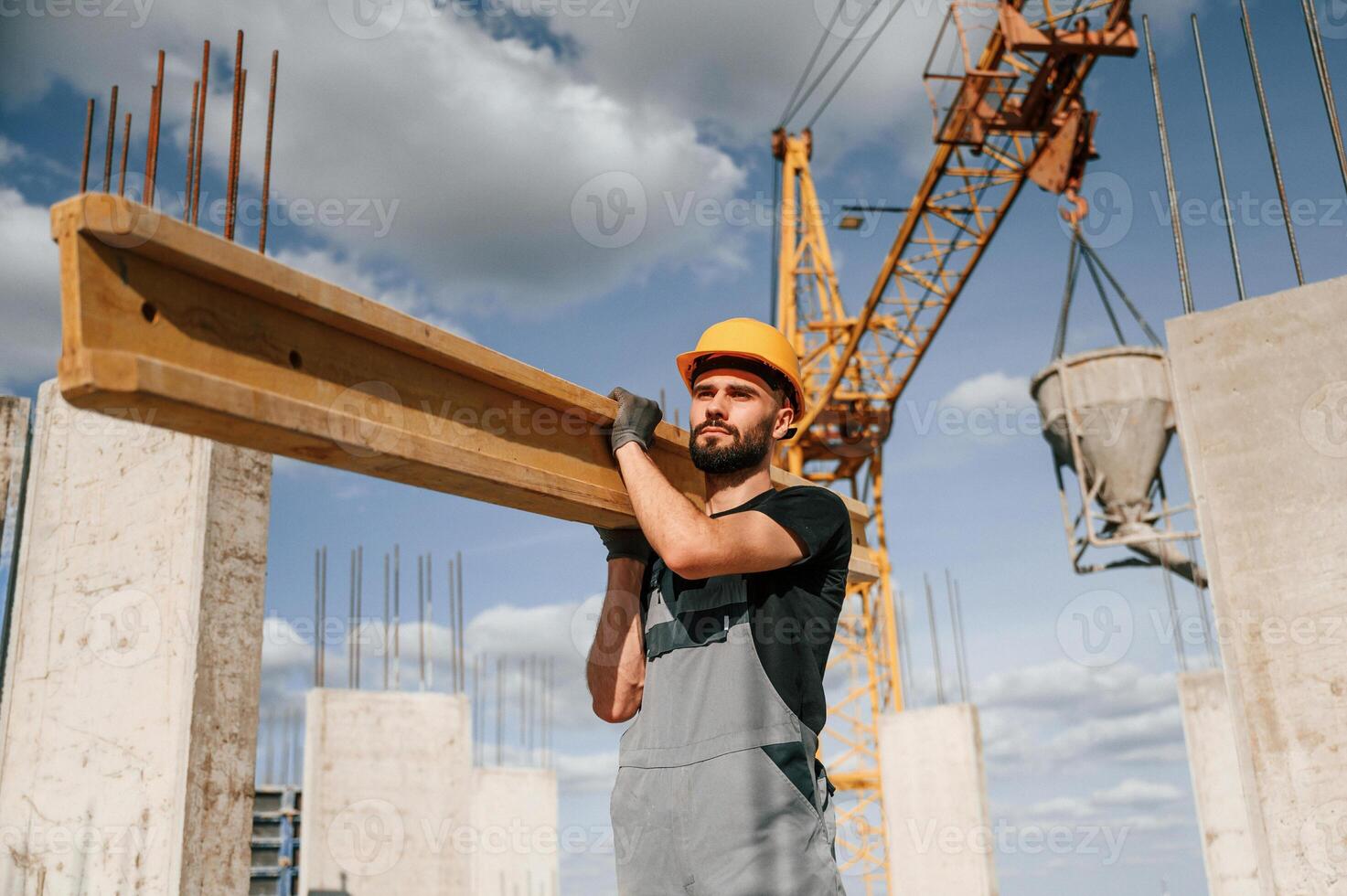Front view ,of man that is in uniform holding ,wooden plank on the construction site photo