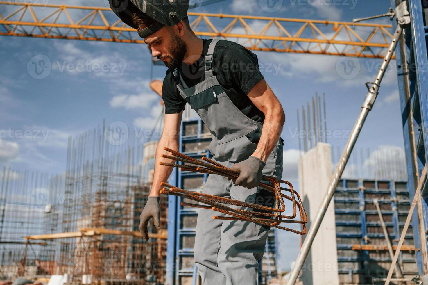 Working with rusty metal ,pieces. Man in uniform is on the construction site photo