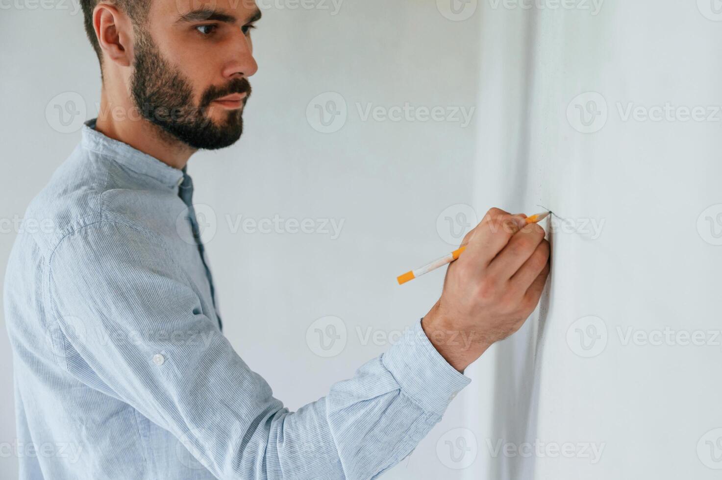 Doing marks by pencil on the wall. .The man is making repairs in the apartment photo