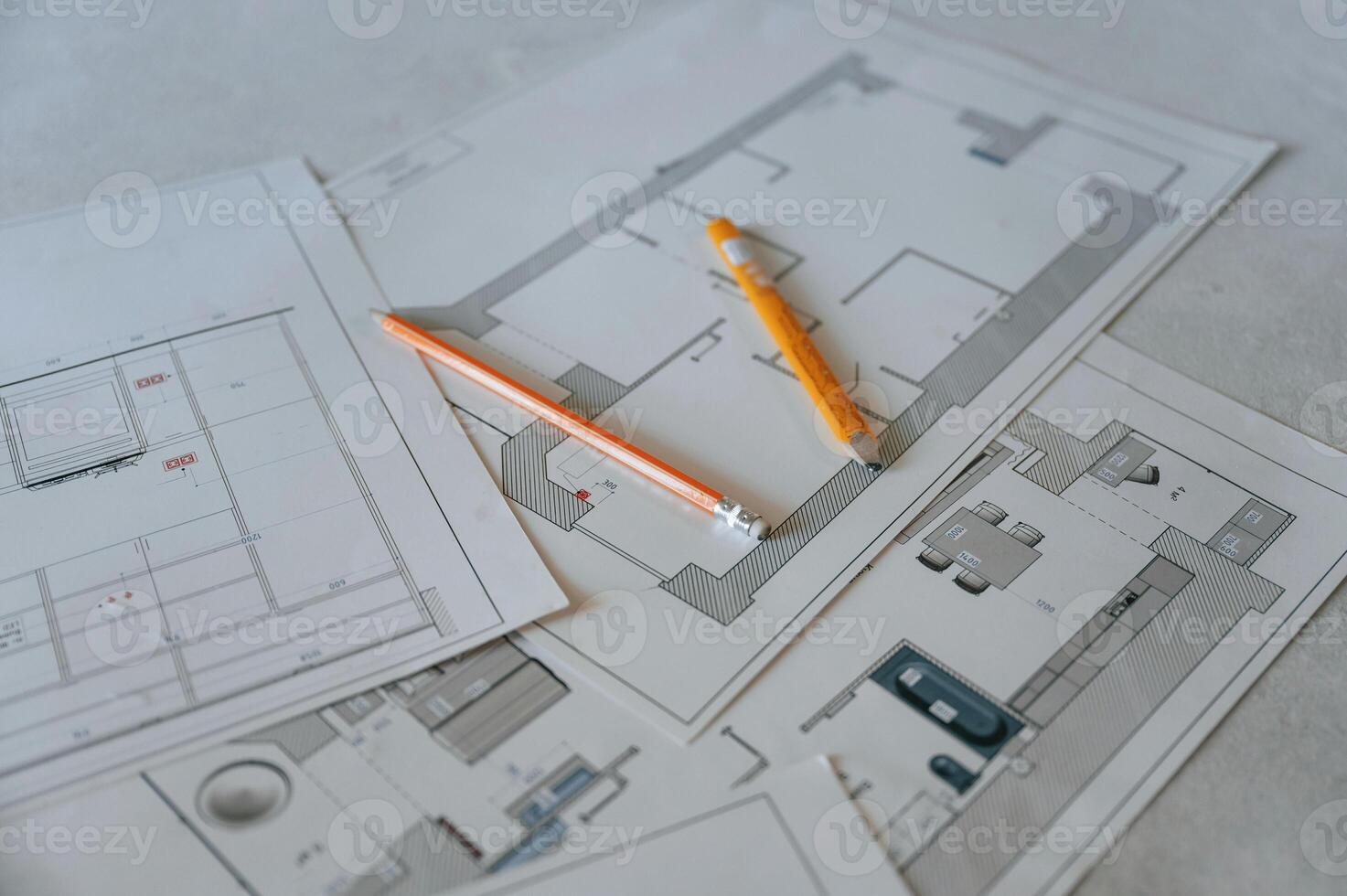 Close up view of plan of building repaiting and contruction that is on the floor with yellow pencils on it photo