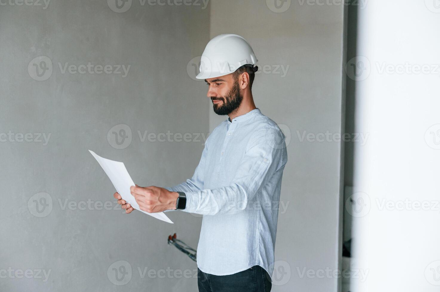 Holding ,and ,reading document. .The man is making repairs in the apartment photo