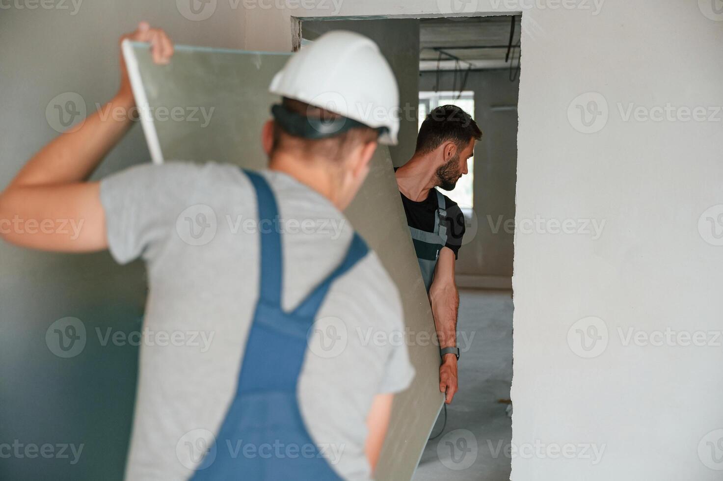 Moving construction pieces by hands. Two men is making repairs in the apartment together photo