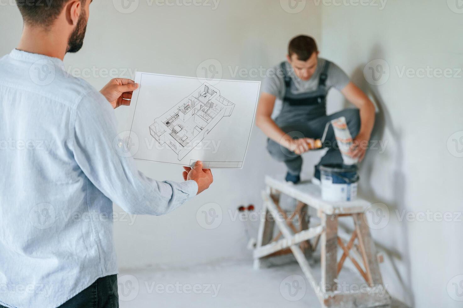 Working according to a plan. Two men is making ,repairs in the apartment together photo
