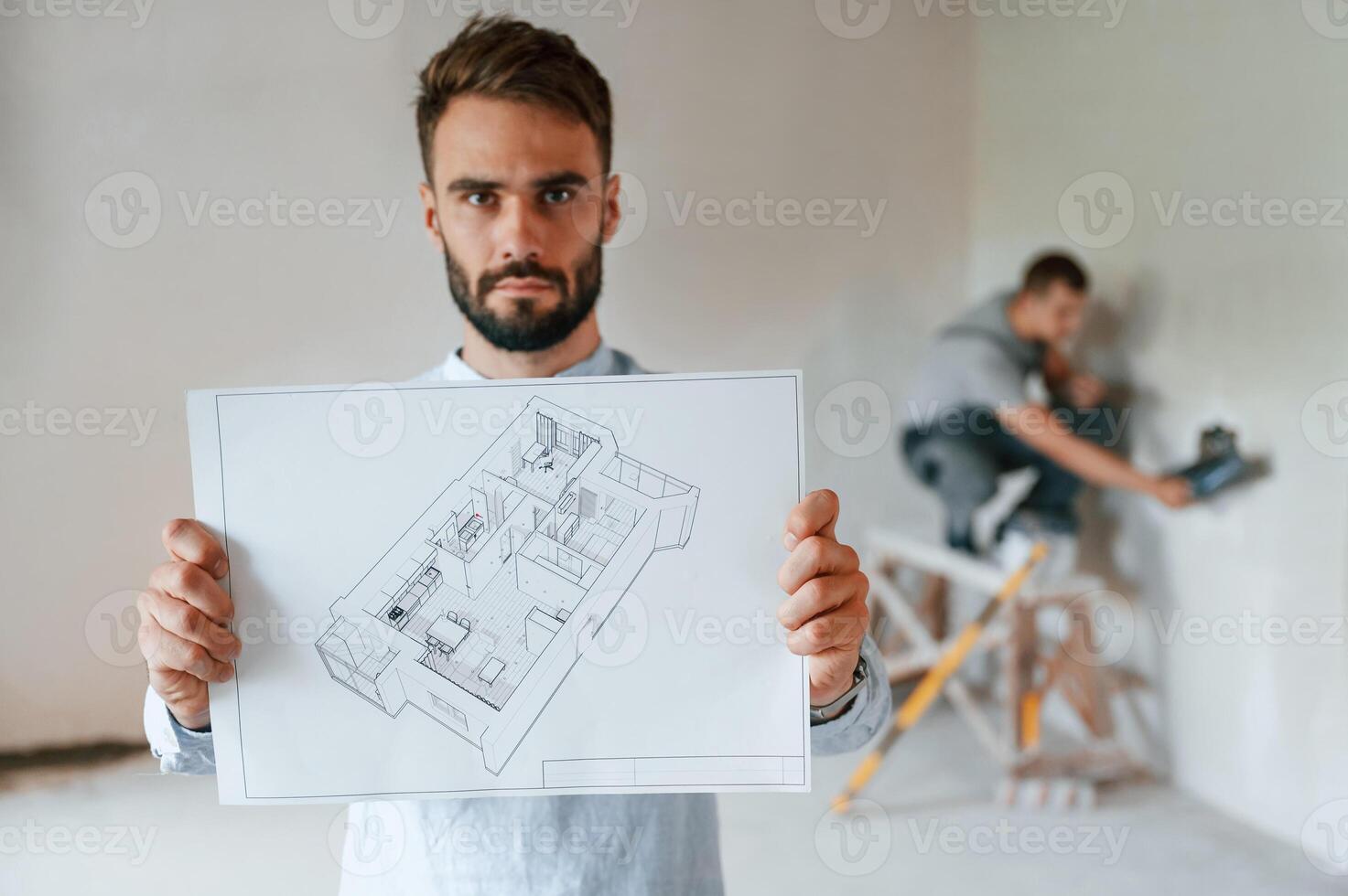 Working, according to a plan. Two men is making repairs in the apartment together photo