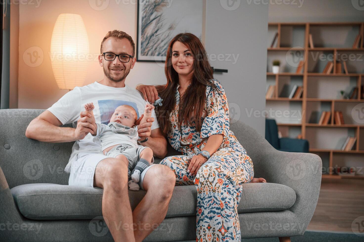 On the sofa together. Happy couple with their newborn boy is at home photo