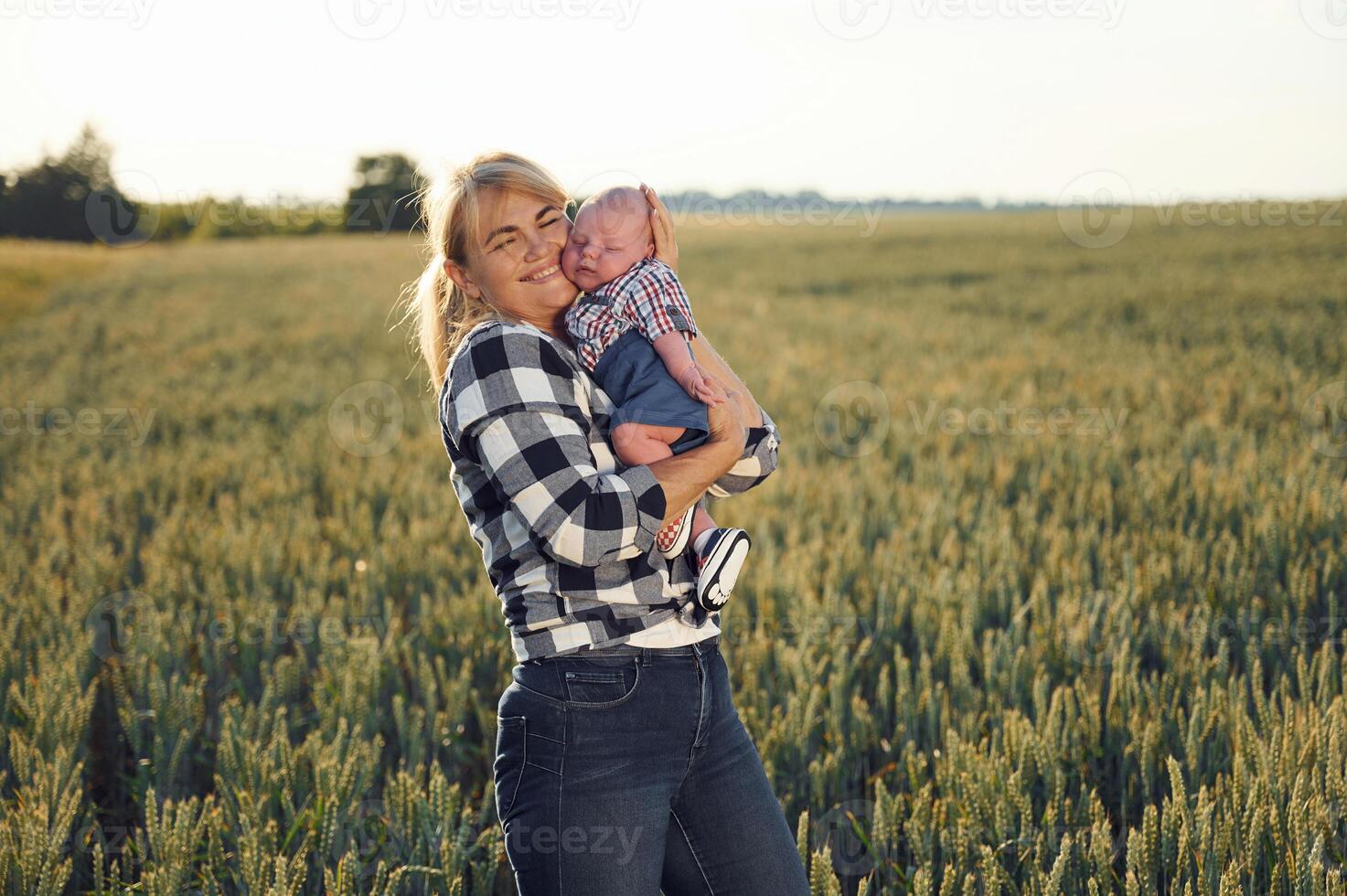Standing ,and smiling, Happy, woman on the agricultural field is with little baby in the hands photo