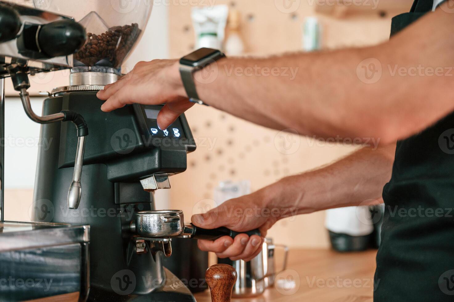 Putting raw coffee into machine to boil. Barista in the cafe. Close up view photo