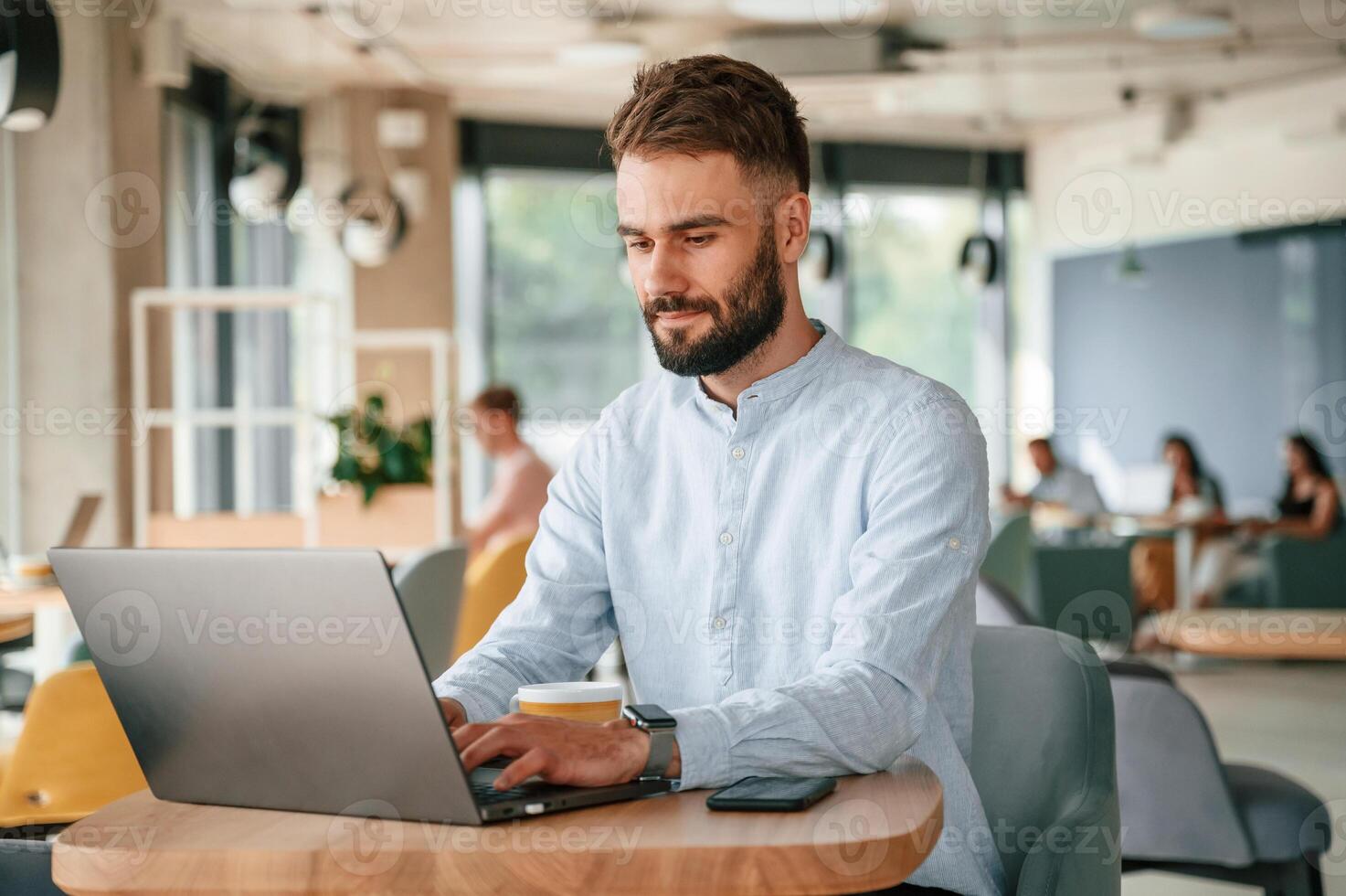 Young ,man is sitting in the cafe and working by using laptop photo
