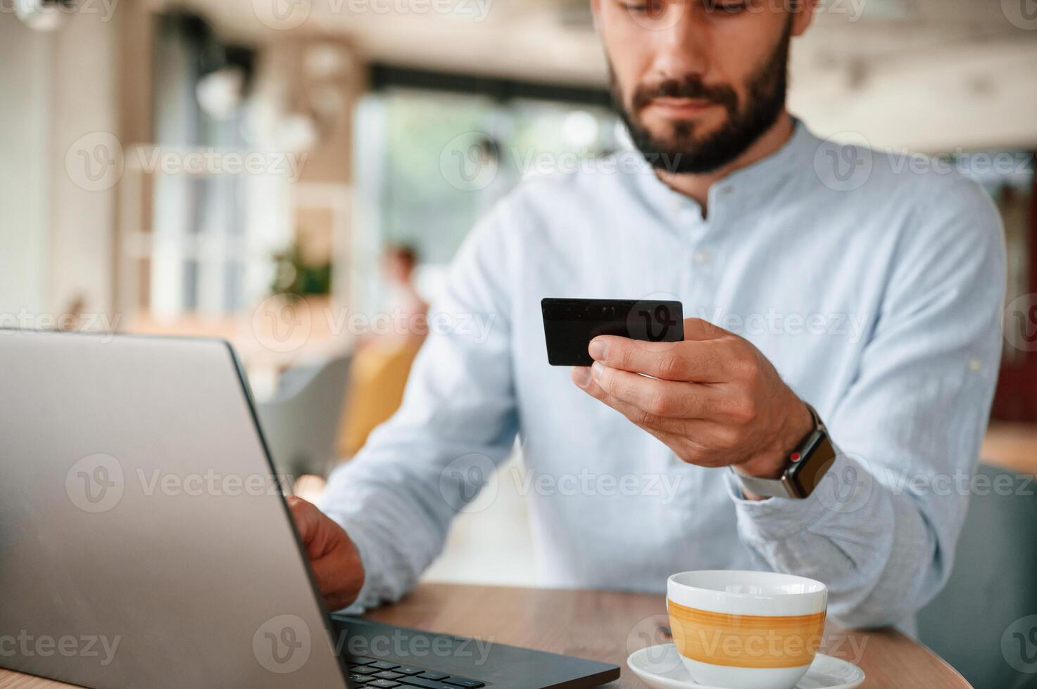Making, payment, by credit card. Young man is sitting in the cafe and working by using laptop photo
