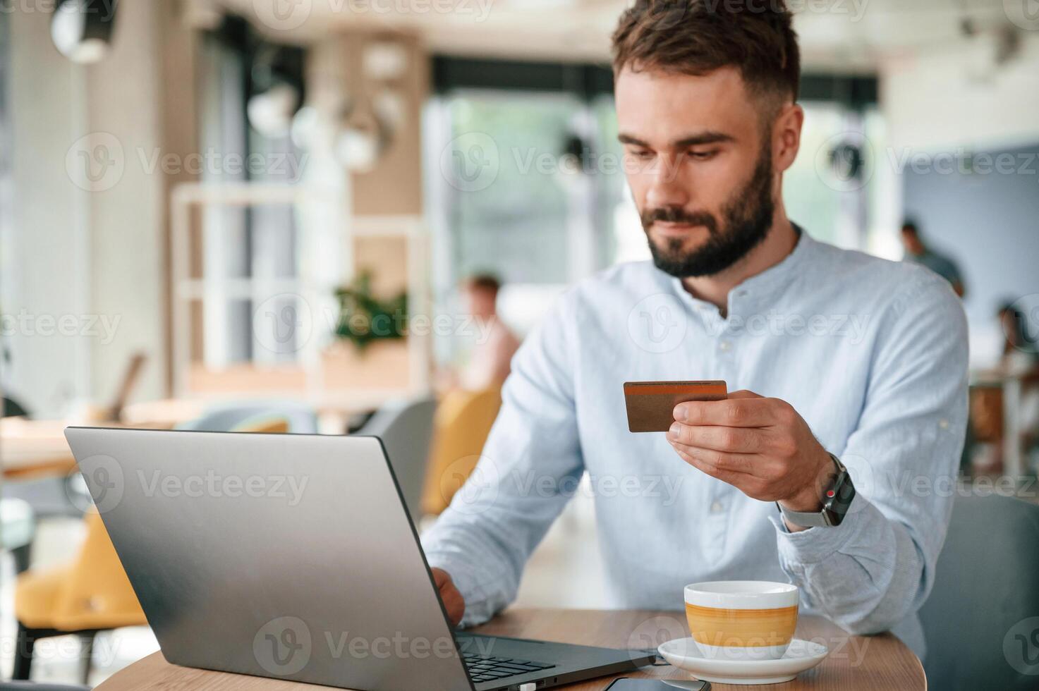 Making ,payment by credit card. Young man is sitting in the cafe and working by using laptop photo