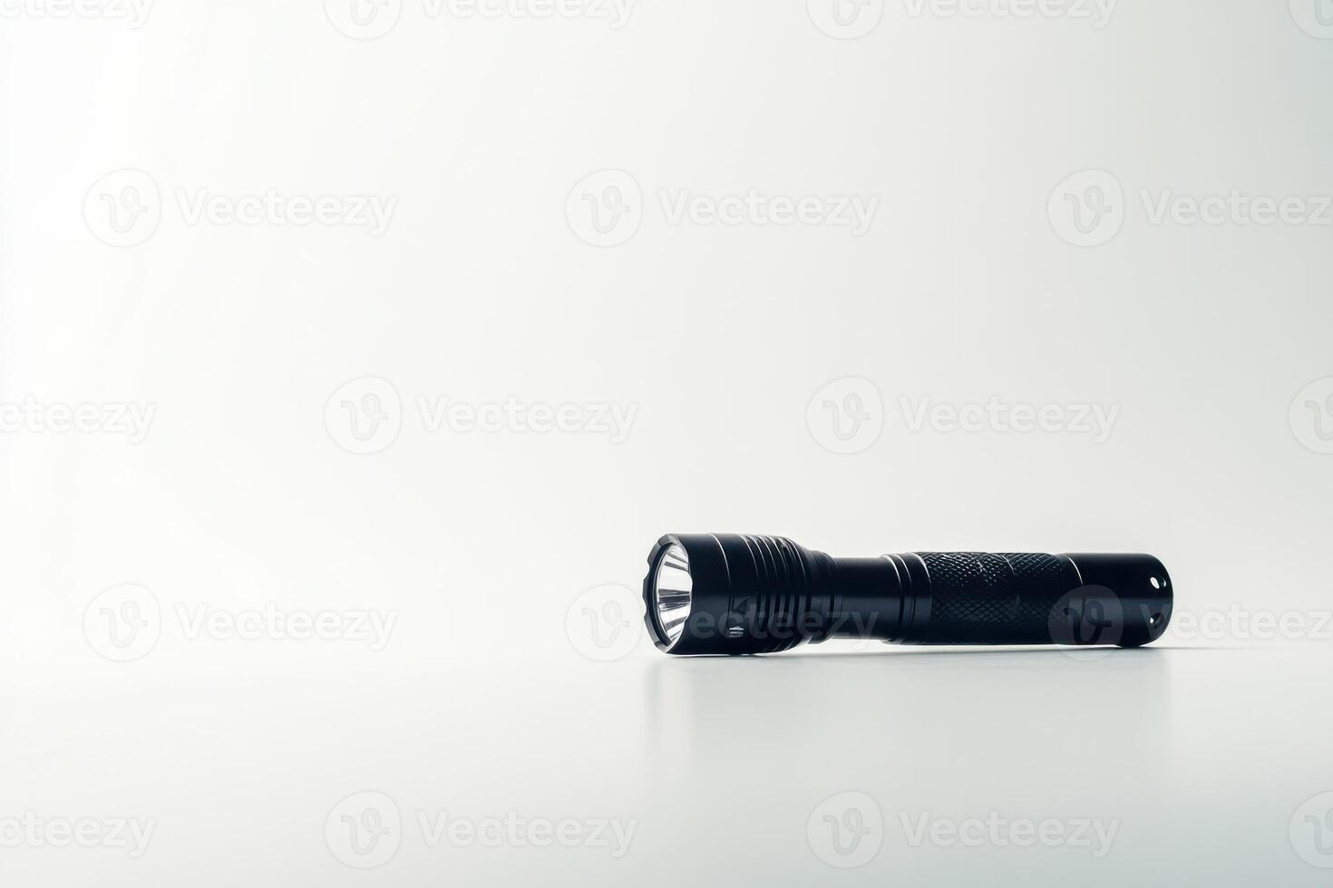 A flashlight is sitting on a table in front of a white background photo