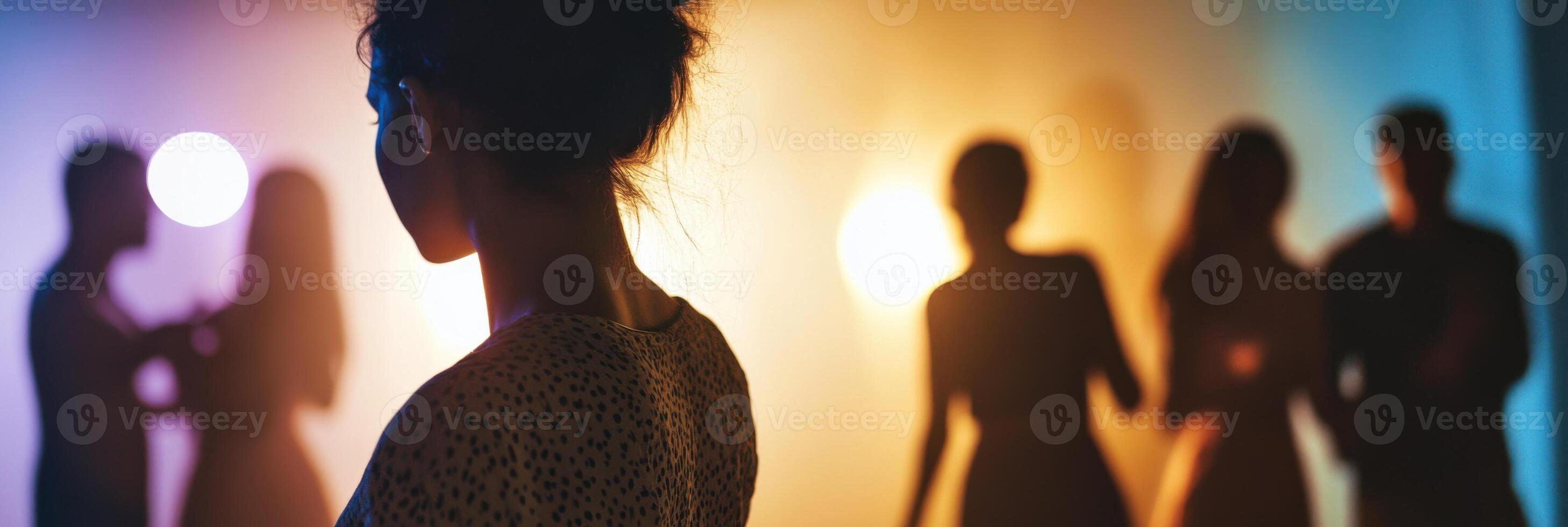 A silhouette of a woman standing in front of a group of people photo