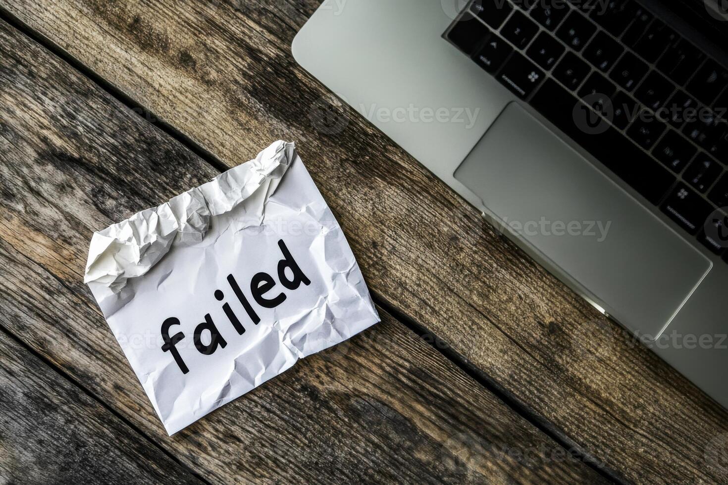 Crumpled paper with failed written on it beside a laptop reflecting fear and aspiration in a workspace photo