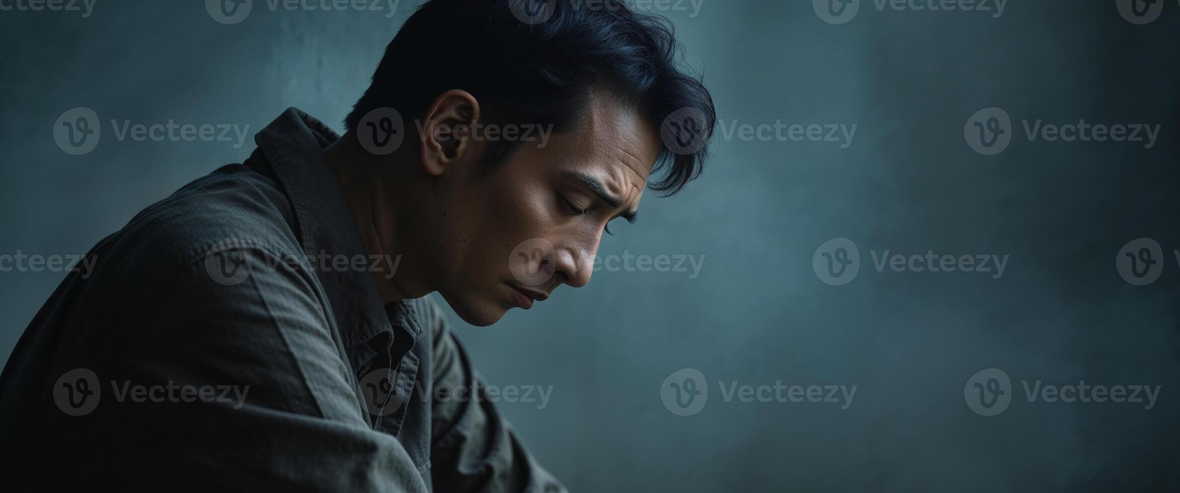 A man in a grey shirt is looking down photo