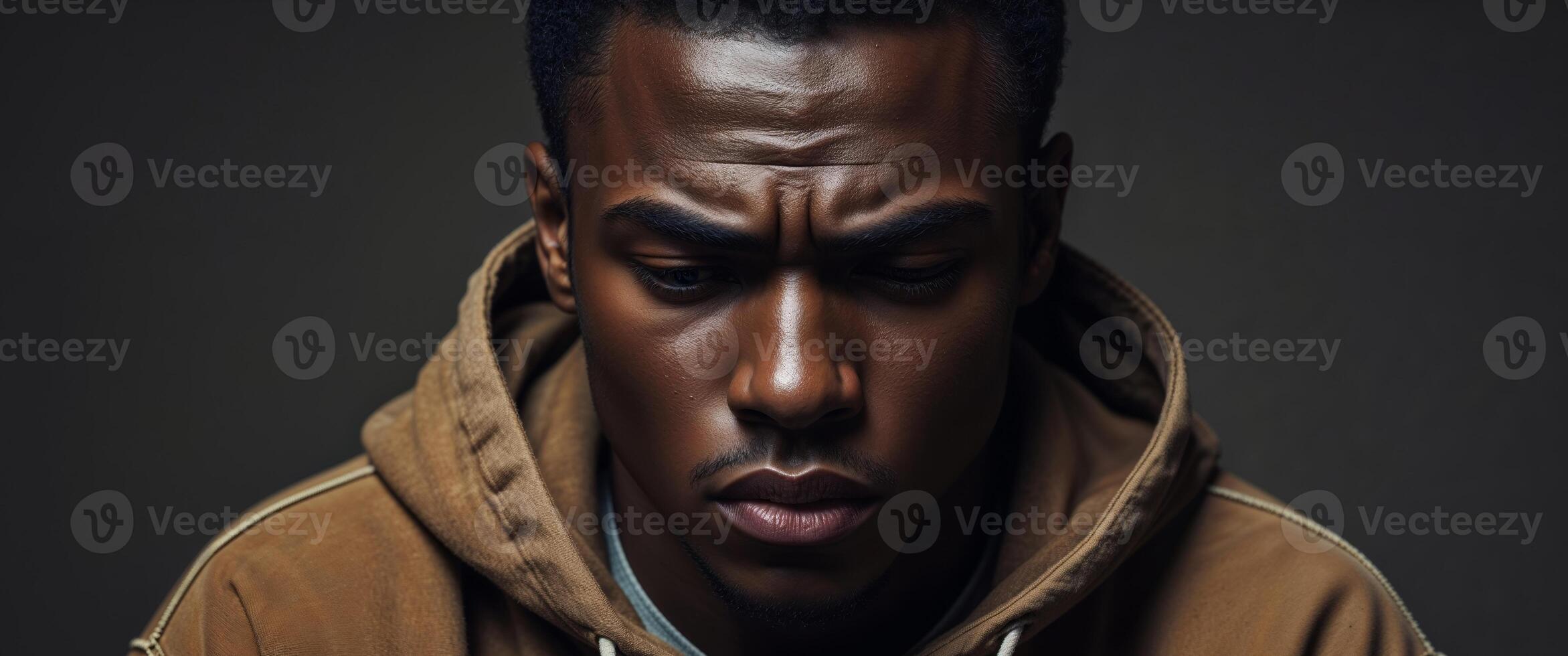 A man in a brown hoodie looking down photo