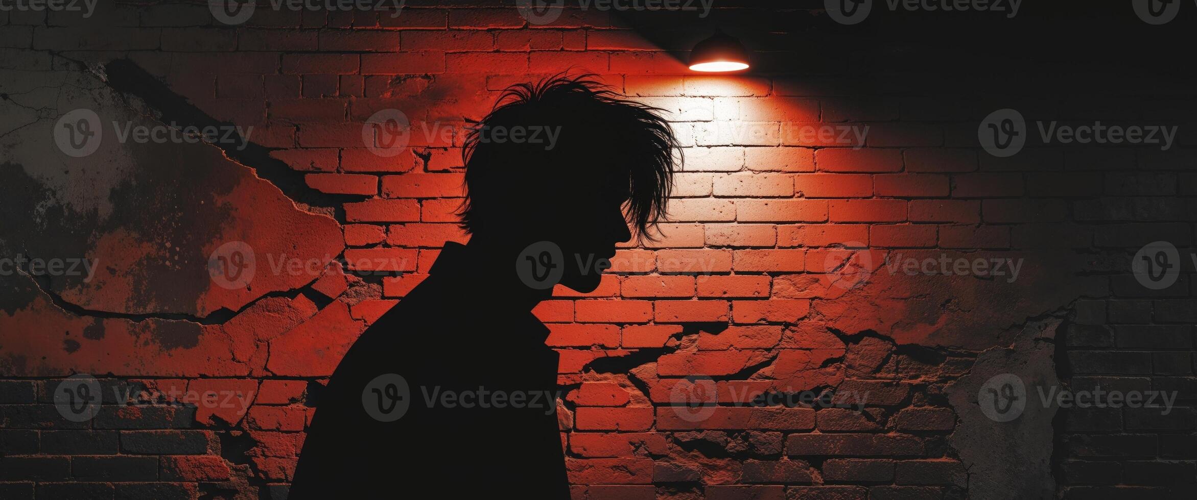 Silhouette of a man casting a shadow on a weathered brick wall in an urban setting with dramatic lighting photo