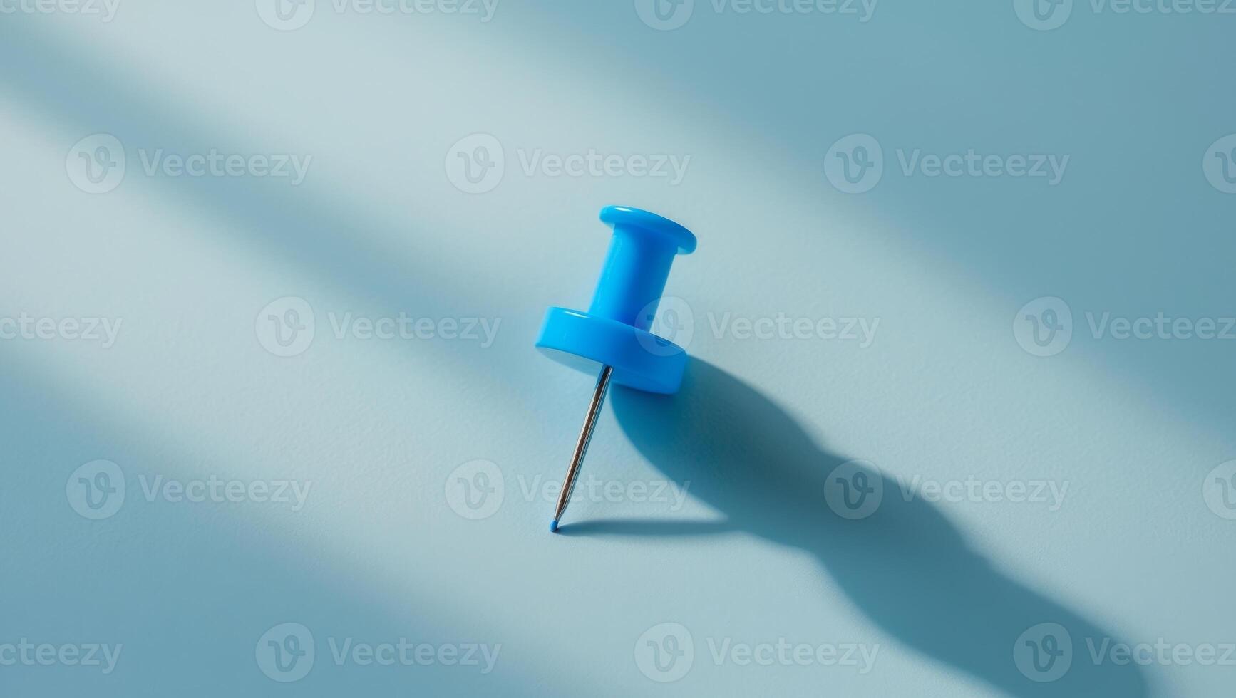 A blue push pin on a blue surface photo