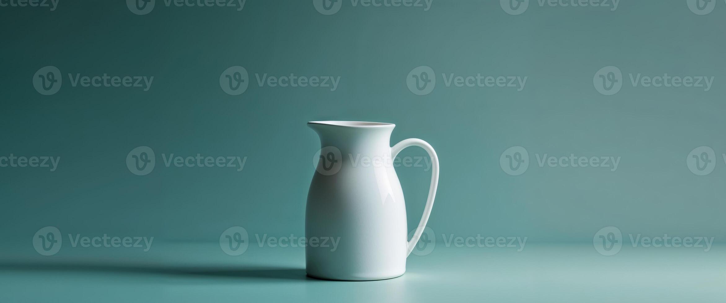 A white pitcher sitting on a table against a blue background photo