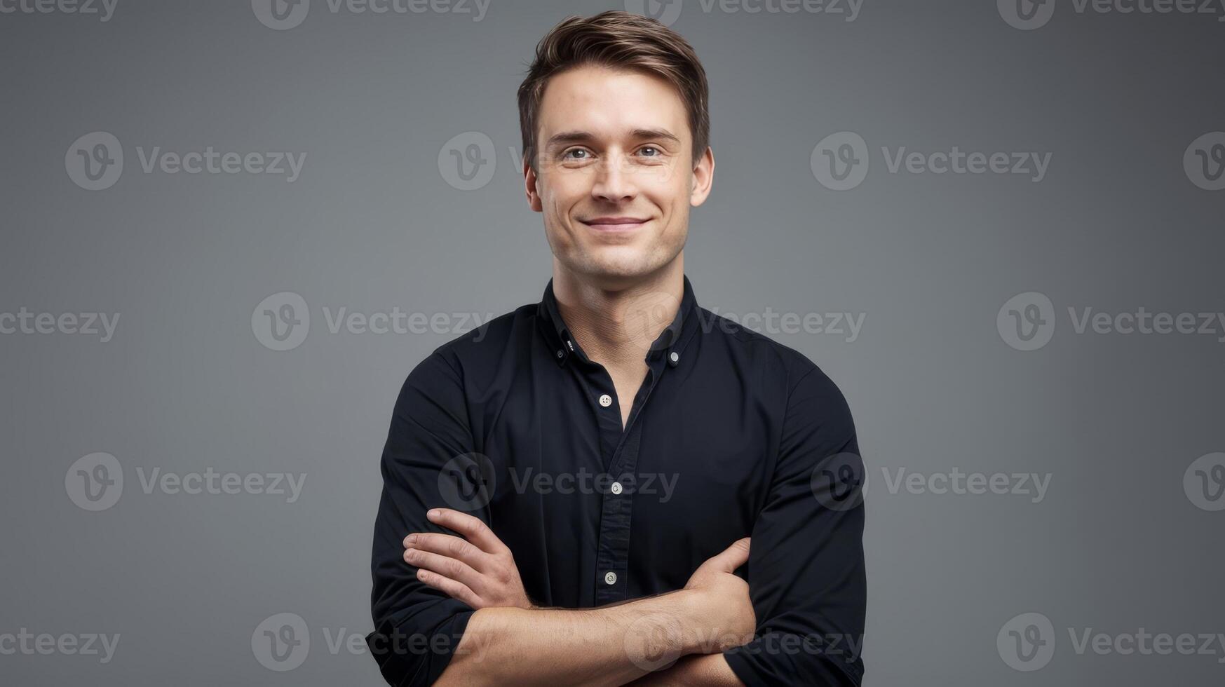 Portrait of a young man with his arms crossed on a gray background photo