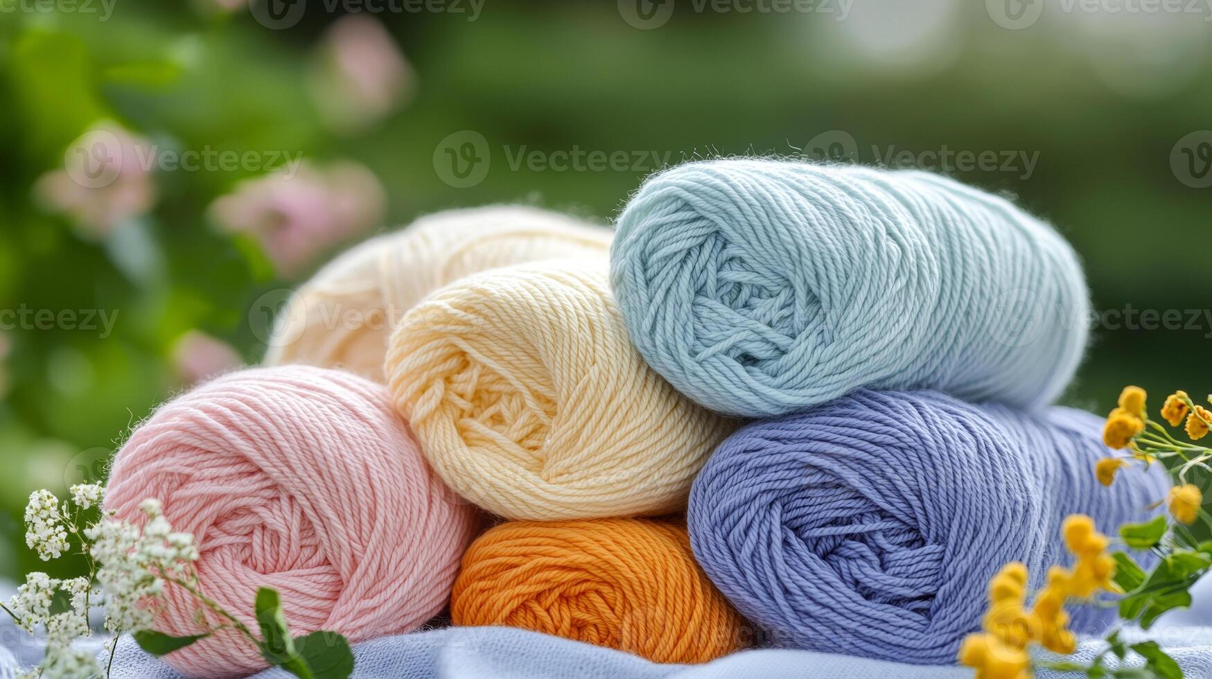 Soft pastel yarn balls stacked outdoors with flowers, creating serene and creative atmosphere photo