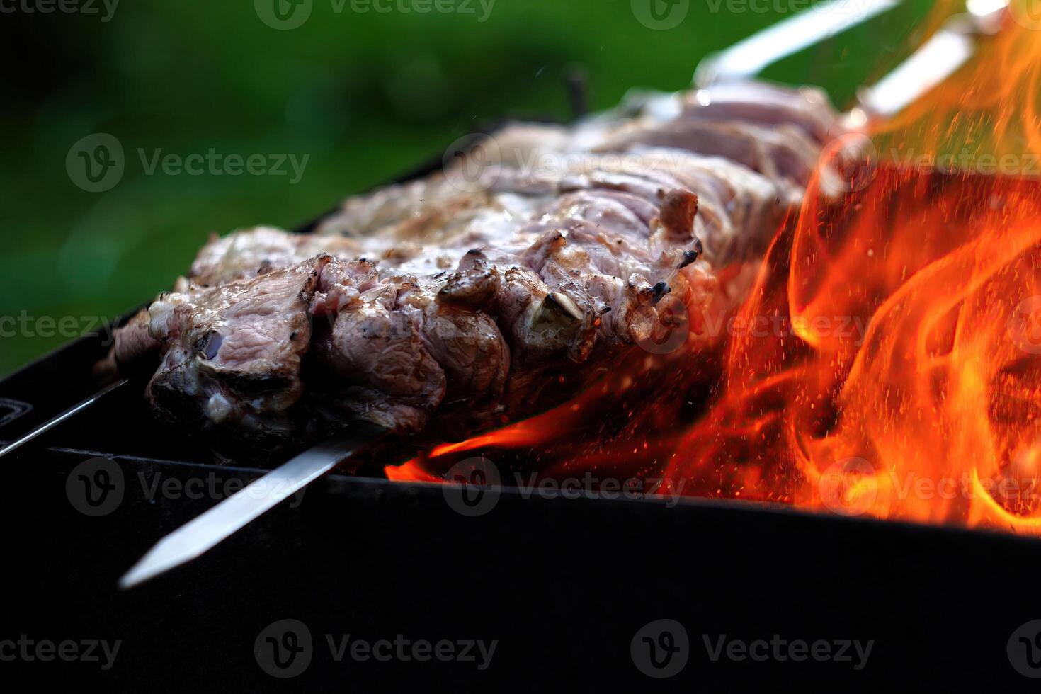 Grilling meat over open flames during a summer cookout with friends photo