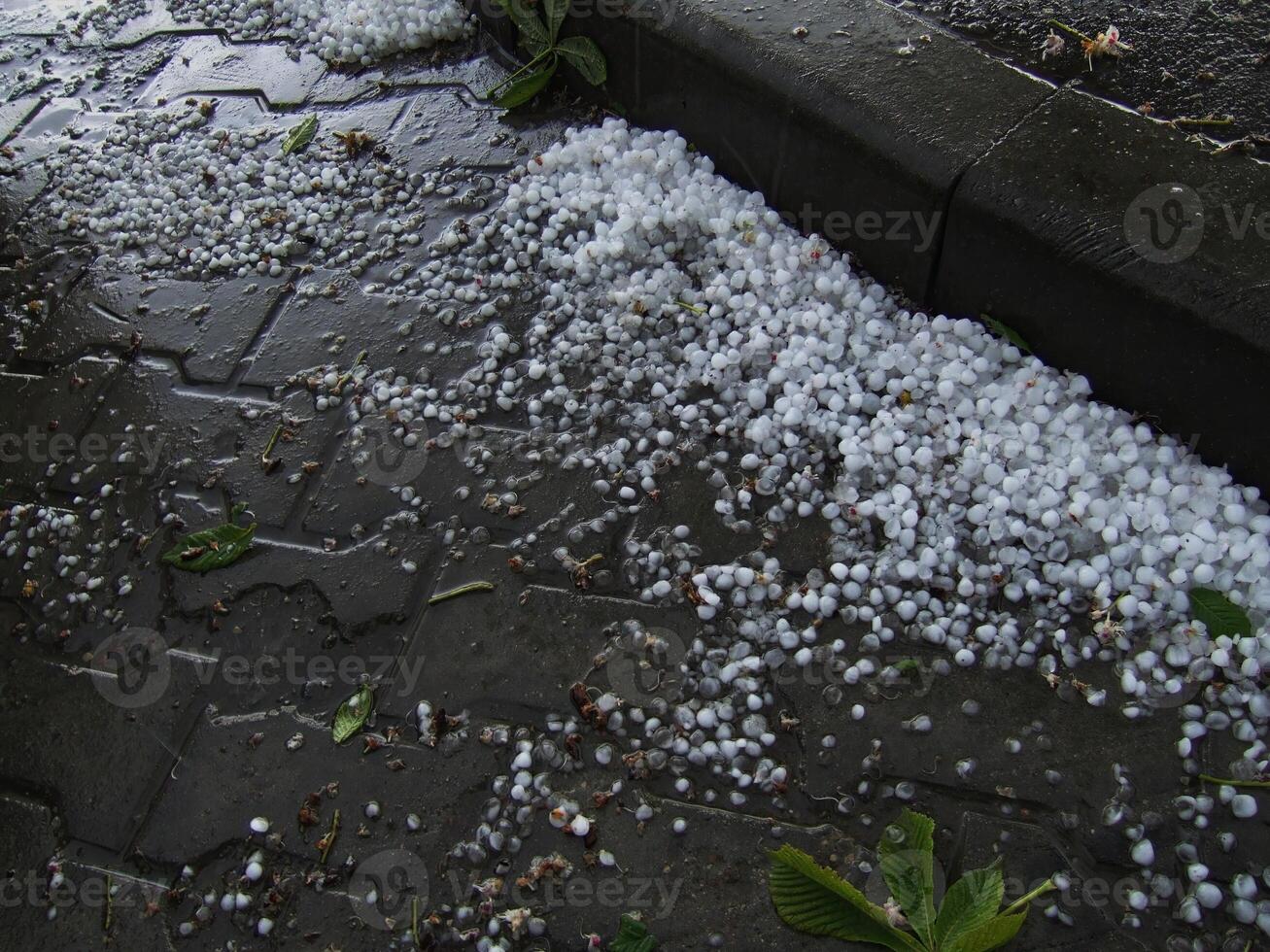 Hail stones accumulate on a sidewalk after intense storm in urban area photo
