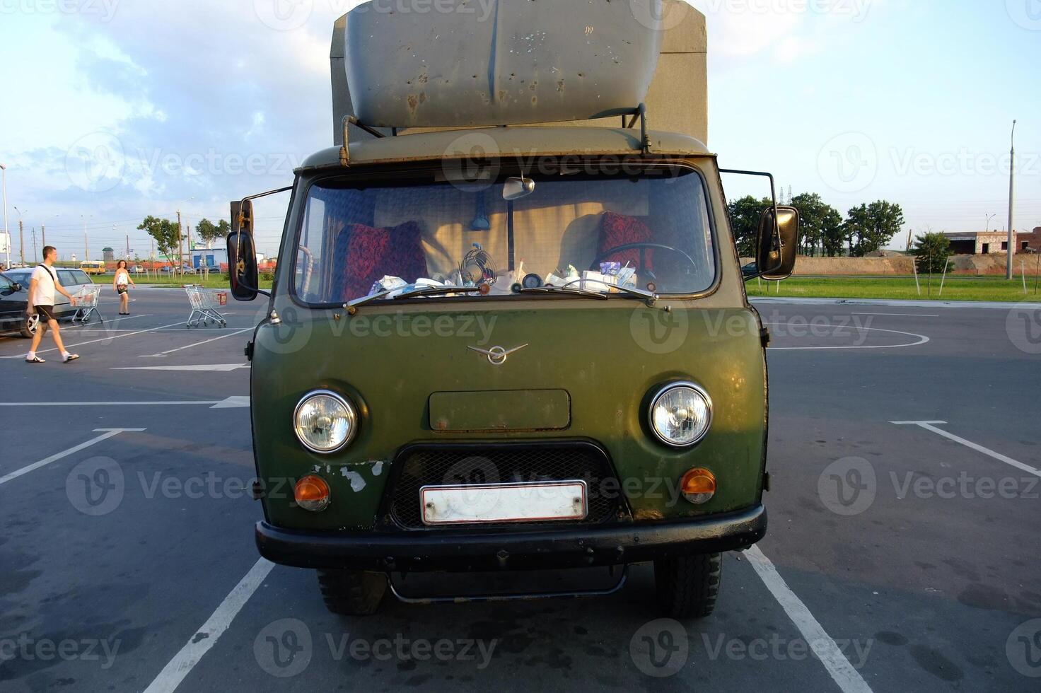 Vintage military green van parked in a public area during daytime at an open space photo