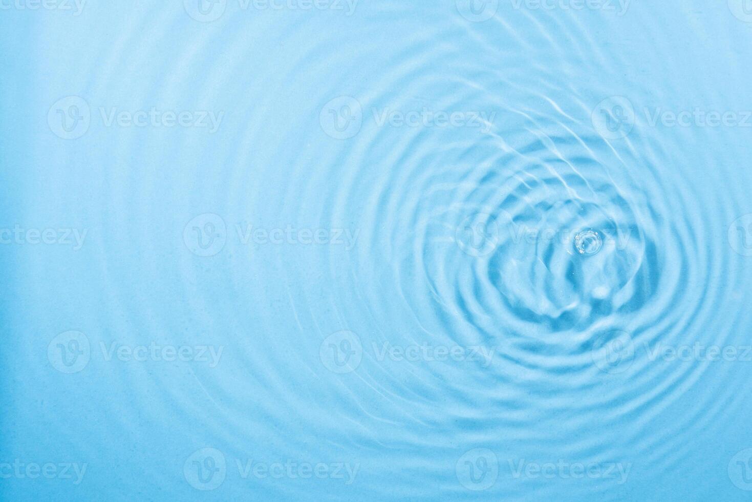 water droplet waves expanding on the water surface illuminated with blue light photo