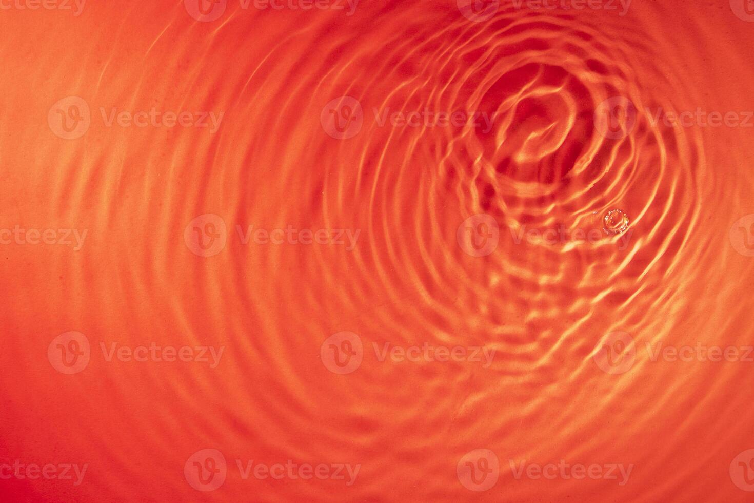 concentric waves of water droplets spreading over the surface of the water illuminated with red light photo