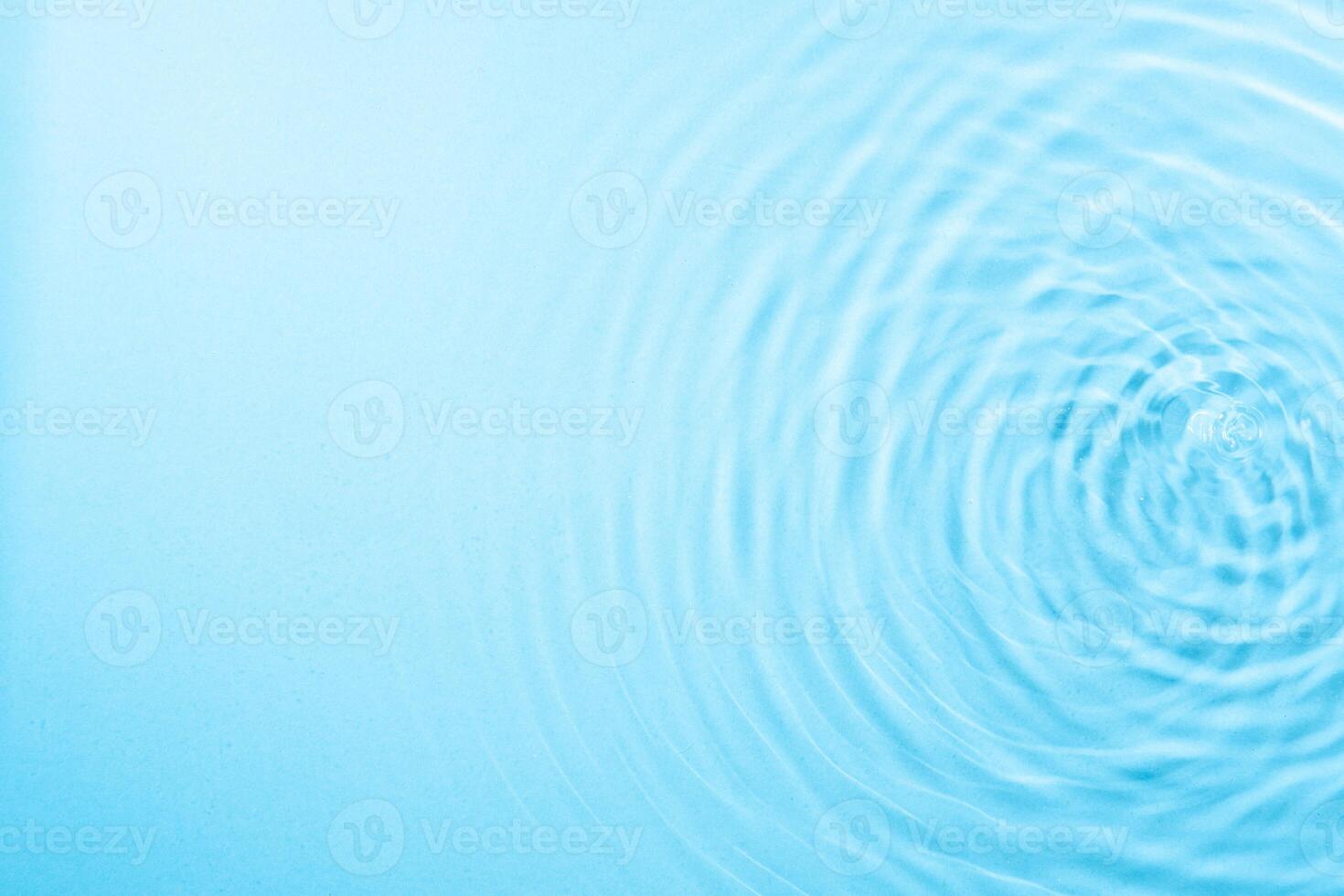 waves of water droplets expanding on the surface of the water illuminated with blue light photo