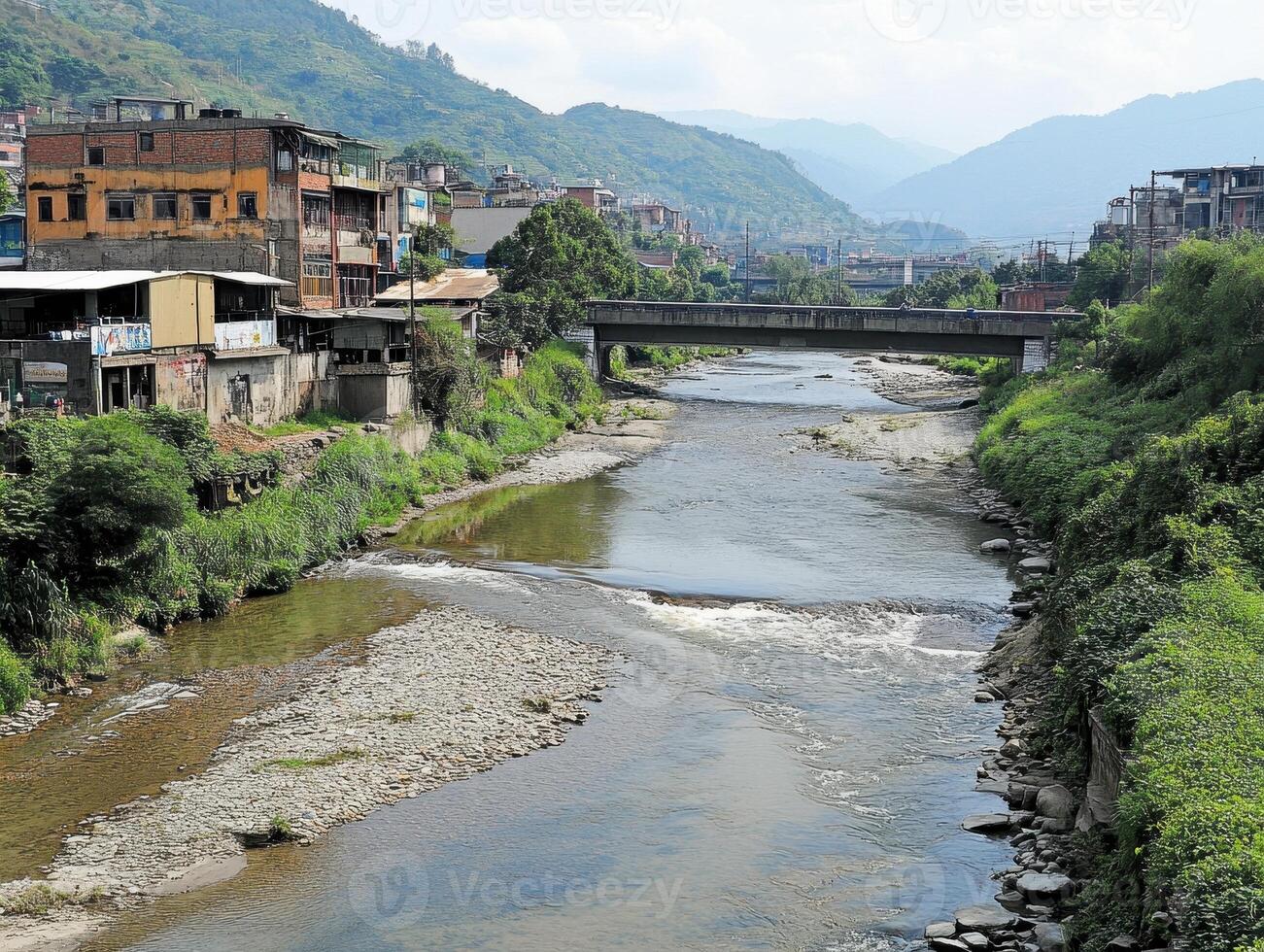 Emerging market economic trends Concept. A scenic view of a river flowing through a small town, flanked by greenery and buildings, with mountains in the background under a partly cloudy sky. photo