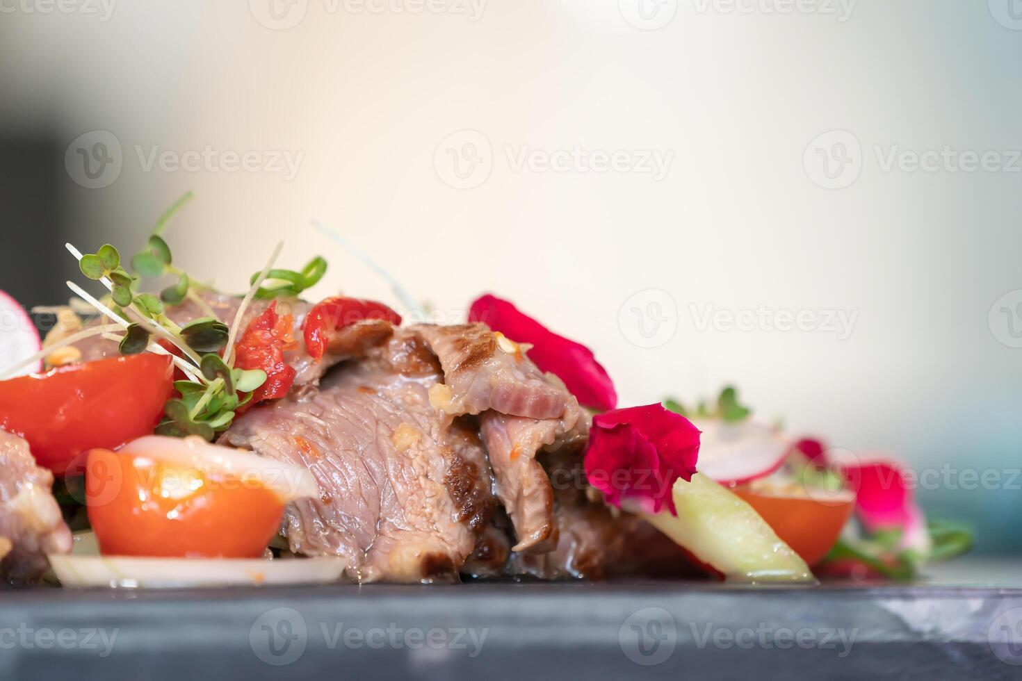 Close up to Spicy Thai Beef Salad garnished on to p with cress and micro herb was put on a rectangular stone plate. photo