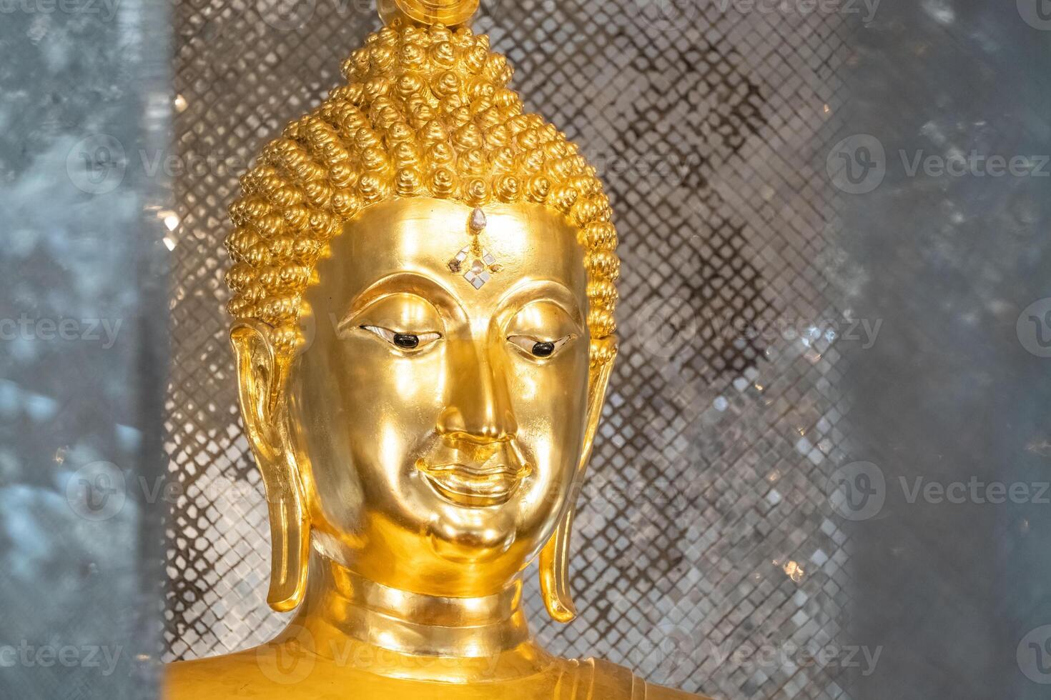 close up of golden Buddha statue is a stunning sig ht to behold. The intricate details and craftsmanship of the sculpture are clearly visible, showcasing the skill and talent of artist who created it. photo