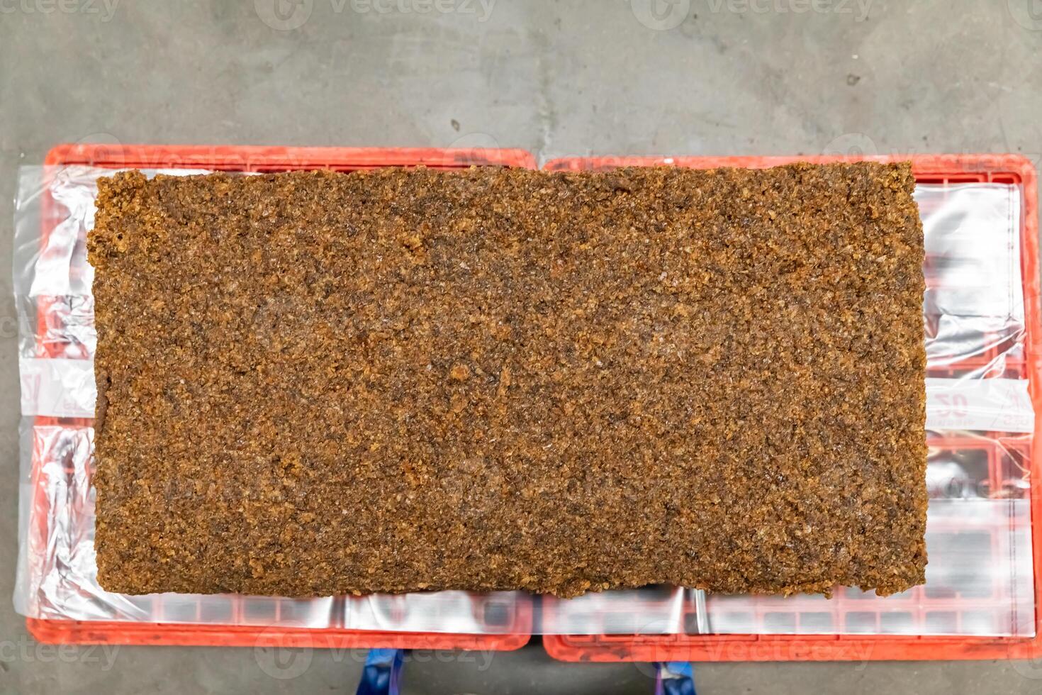 The close up image of the jagged brown natural ra w rubber bales surface, lumpy solid block standard Thai rubber, in a factory. photo