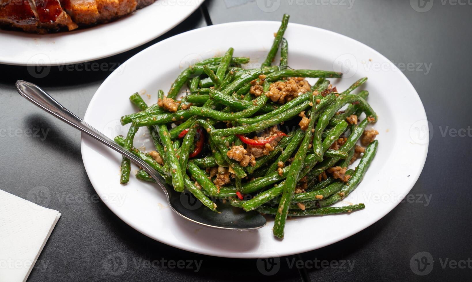 Stir fried string beans with minced pork in a savory garlic sauce, garnished with red chili slices for a flavorful kick. photo